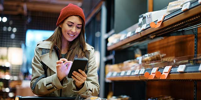 Mujer utilizando su teléfono móvil mientras realiza compras